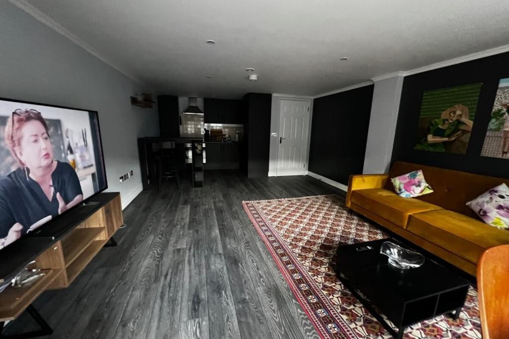 ein Wohnzimmer mit einem Sofa und einem Flachbild-TV in der Unterkunft Beautifully Refurbished 1BD Flat - West Kensington in London