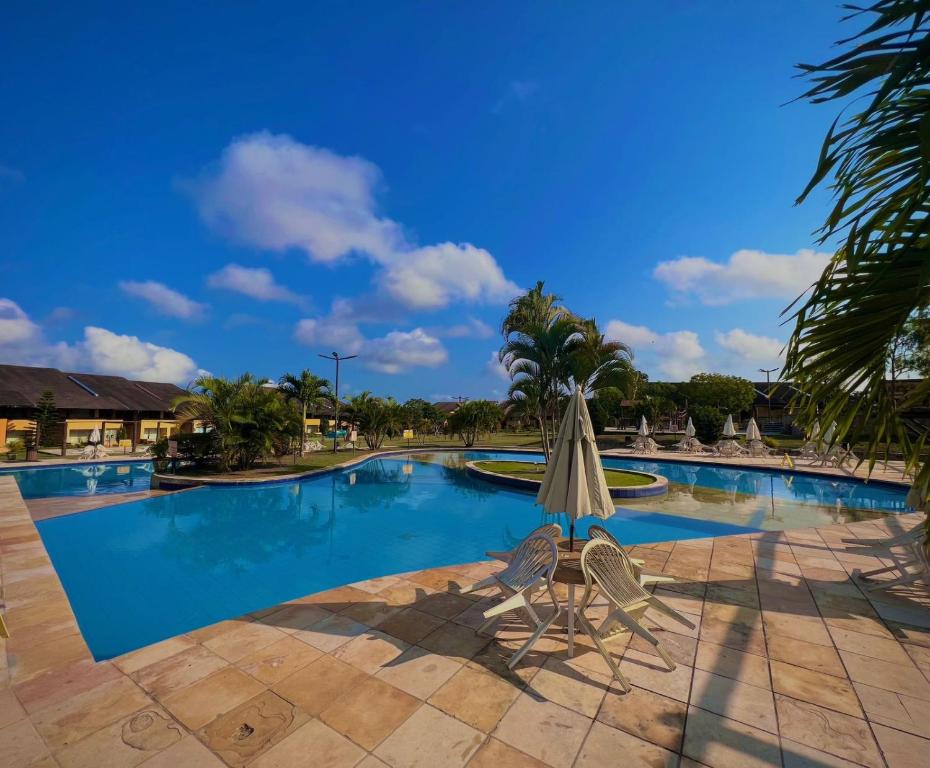 a large swimming pool with an umbrella and a chair at FLAT GRAVATÁ WINTERVILLE 1214 in Gravatá