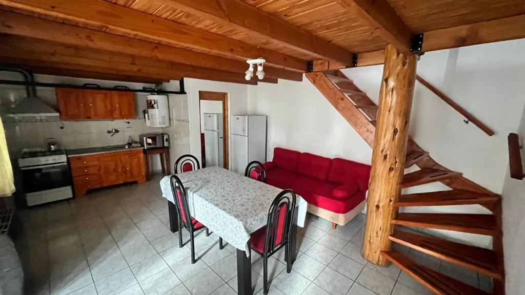 cocina con mesa y sofá rojo en Alojamientos ANSAI 1, en El Bolsón