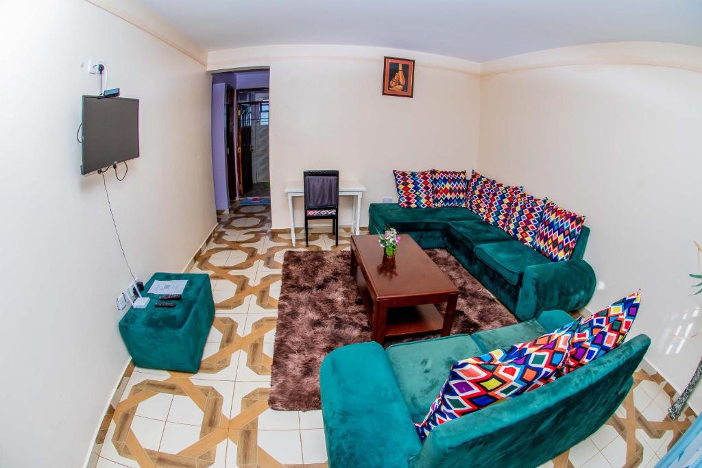 a living room with green couches and a table at A&B Cozy Retreat Kitale in Kitale