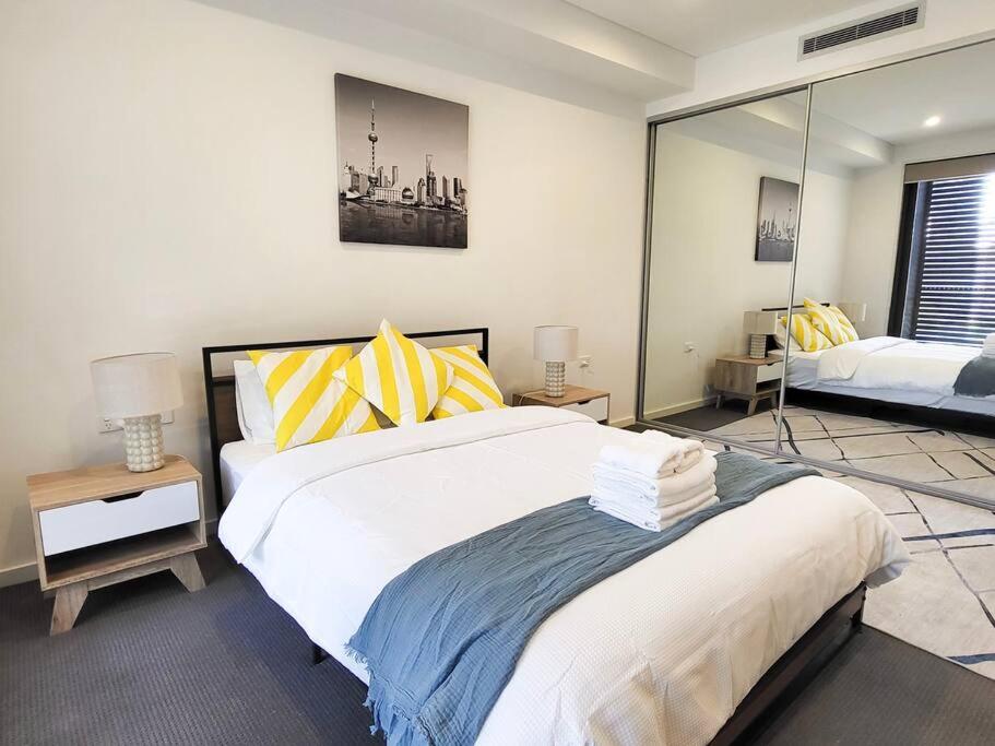 1 dormitorio con 1 cama grande con almohadas amarillas y azules en Modern Elegance: 2 Bedroom Oasis w/ Free Parking, en Epping