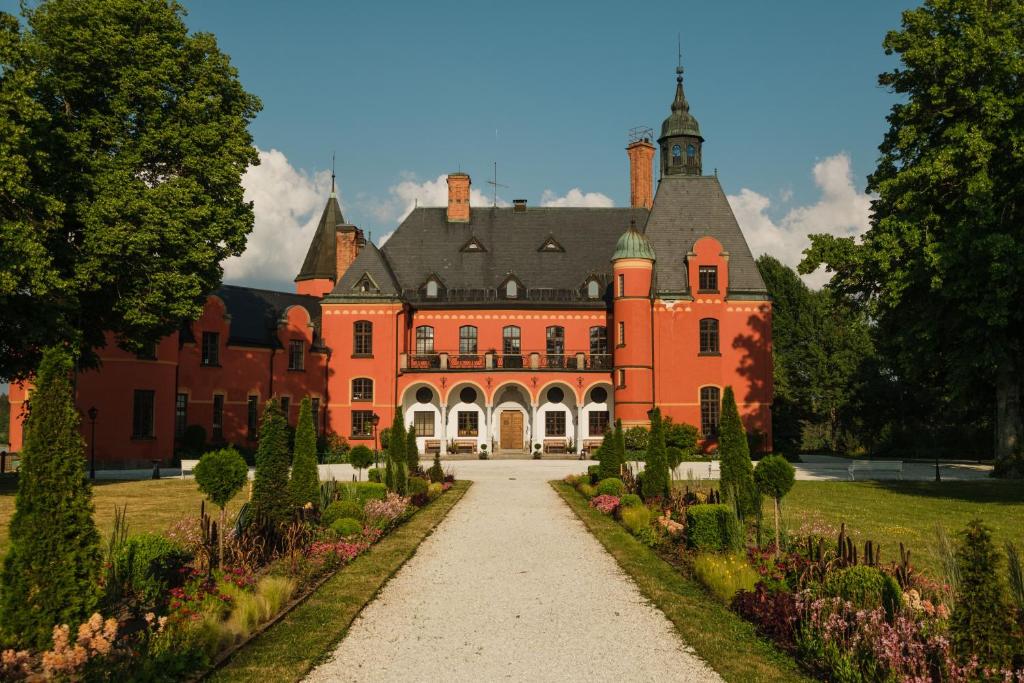 un grand bâtiment orange avec un chemin devant lui dans l'établissement Lejondals Slott, à Bro