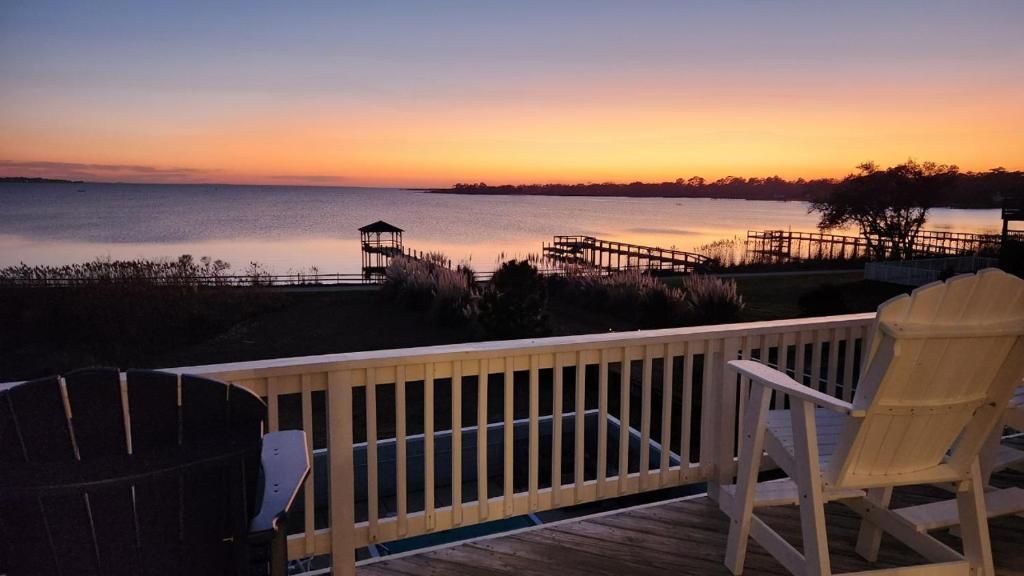a deck with two chairs and the ocean at sunset at No Fee Luxury Pet Friendly 7BR Soundfront retreat with Elevator, Heated Pool and Hot Tub in Kitty Hawk