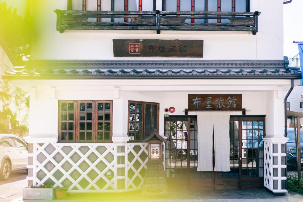 un edificio bianco con un cartello sopra di Nunoya Ryokan a Matsumoto