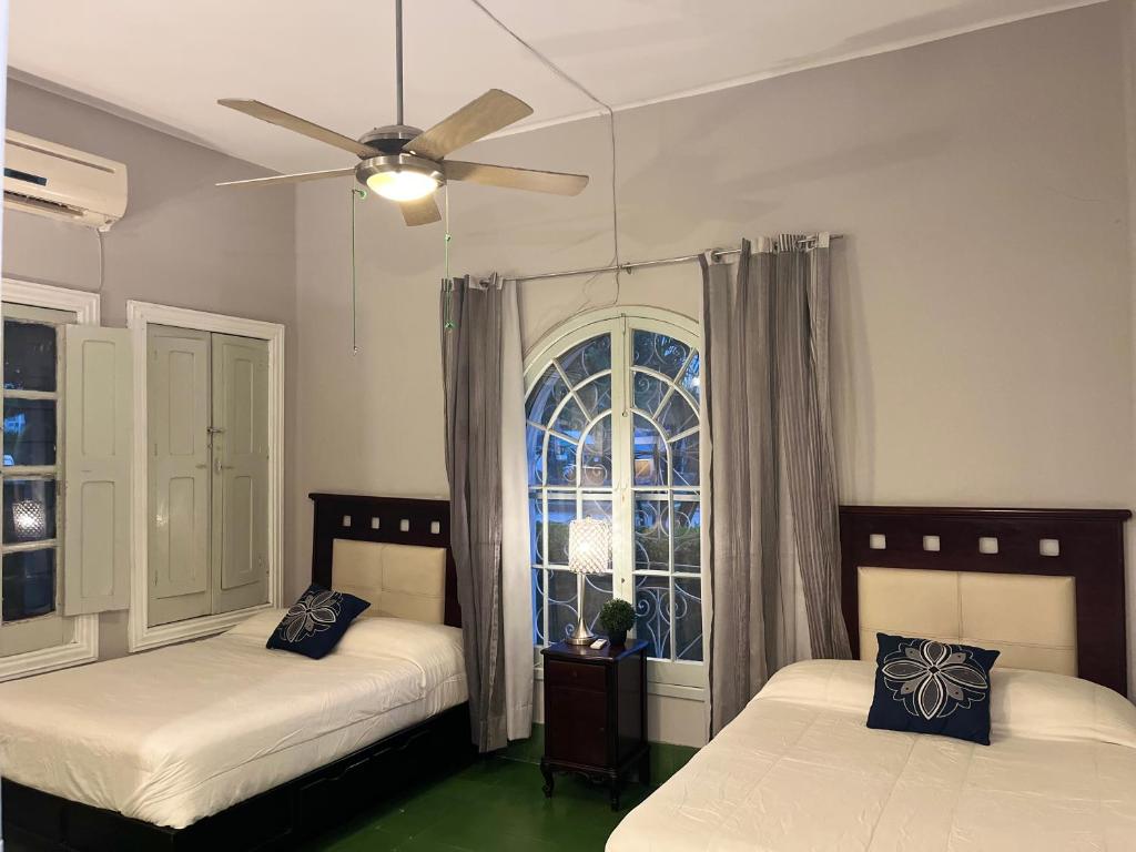 2 camas en una habitación con ventana en Hostal CasaBlanca, en Ciudad Valles