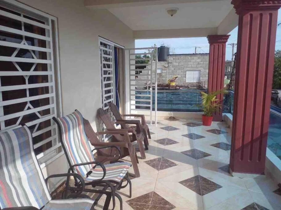d'un balcon avec des chaises à bascule et une piscine. dans l'établissement Espaciosa casa en Matancitas a 3 min de la Playa, à Matancita