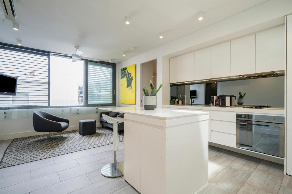 una cocina con armarios blancos y una silla negra en EIGHT TWO NINE TWO V: BONDI BEACH en Sídney