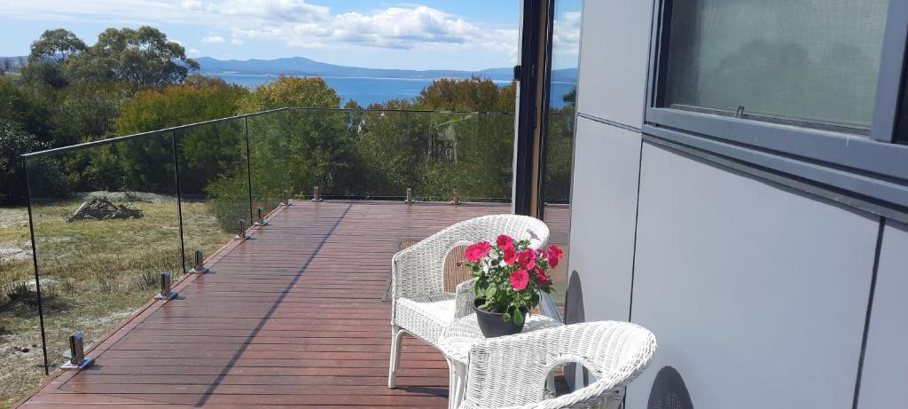 a balcony with two chairs and a vase of flowers at Evergreen Cabin in Primrose Sands