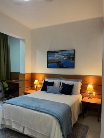 Blue Apartment Copacabana في ريو دي جانيرو: غرفة نوم بسرير كبير مع طاولتين ومصباحين