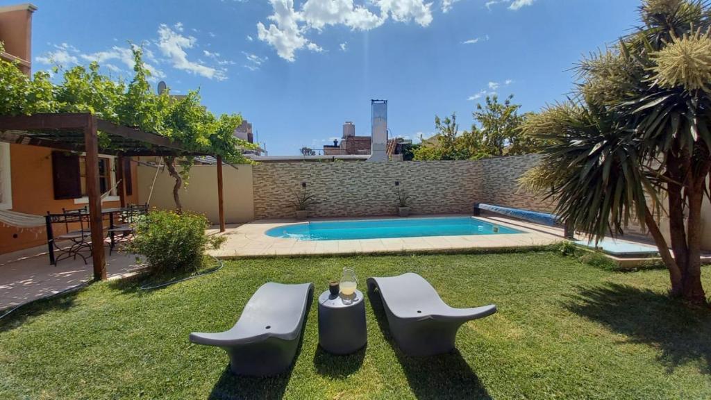 a backyard with a pool and two chairs and a table at Casa Girasoles in Centenario