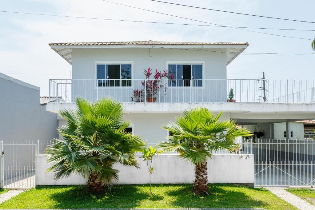 une maison blanche avec des palmiers devant elle dans l'établissement Moradas Palhoça, à Palhoça