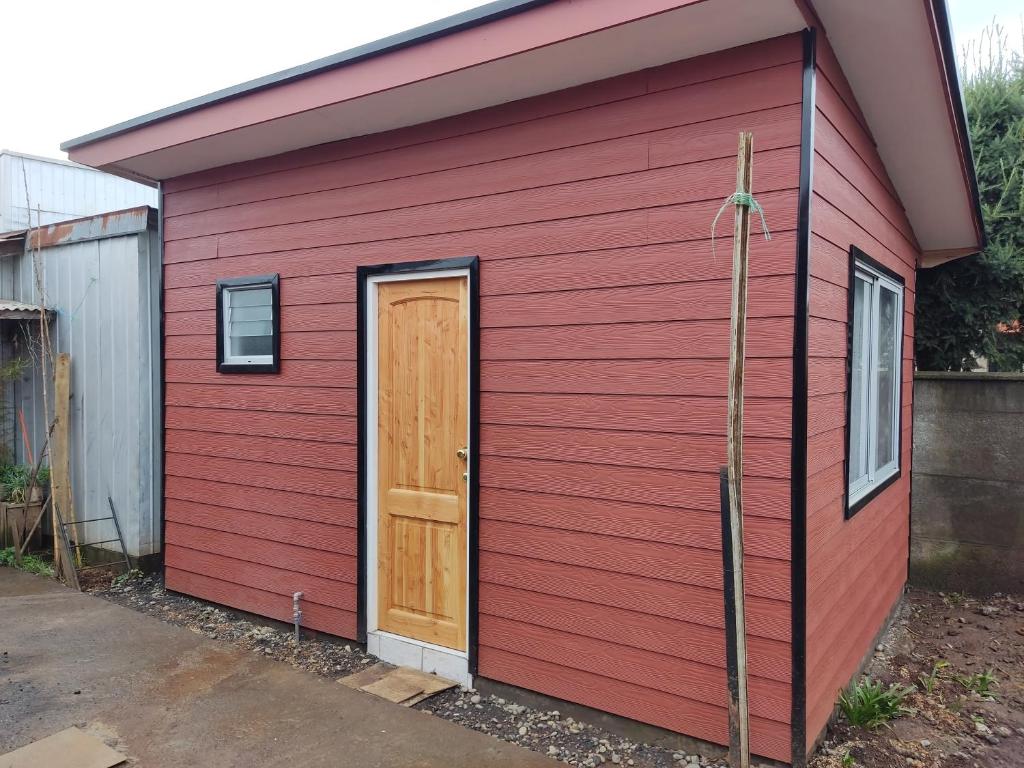 un cobertizo rojo con una puerta de madera. en Mini cabaña nueva independiente en Temuco