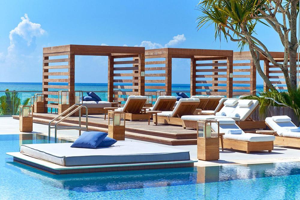 a resort swimming pool with lounge chairs and the ocean at Stunning Studio with Balcony in South Beach in Miami Beach