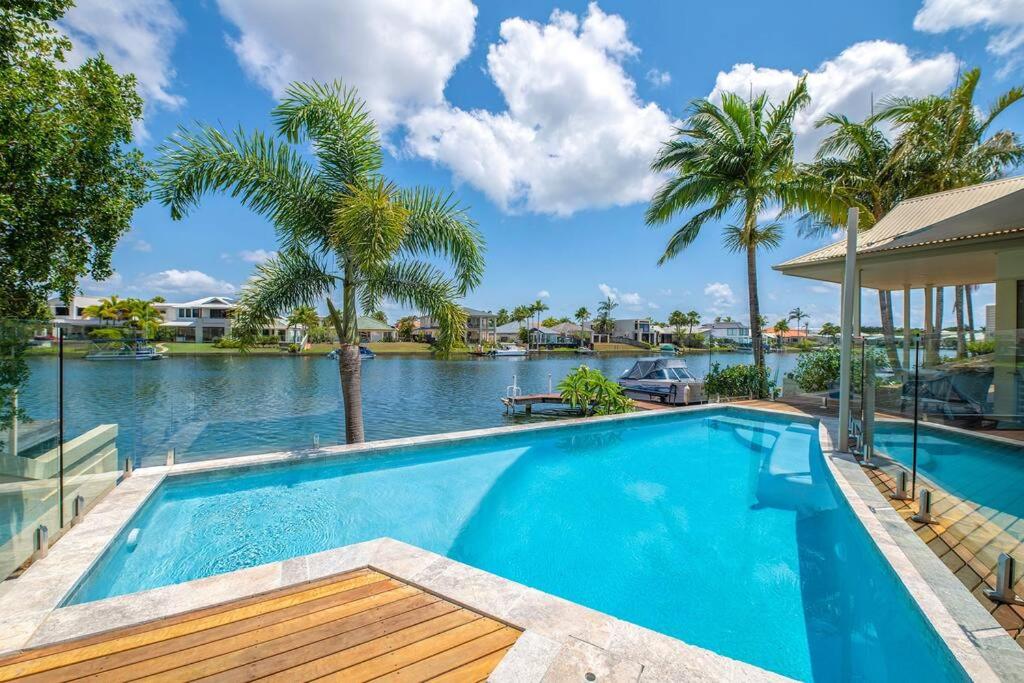 a swimming pool next to a river with palm trees at The Noosa Haven Luxe Waterfront Home in Noosaville
