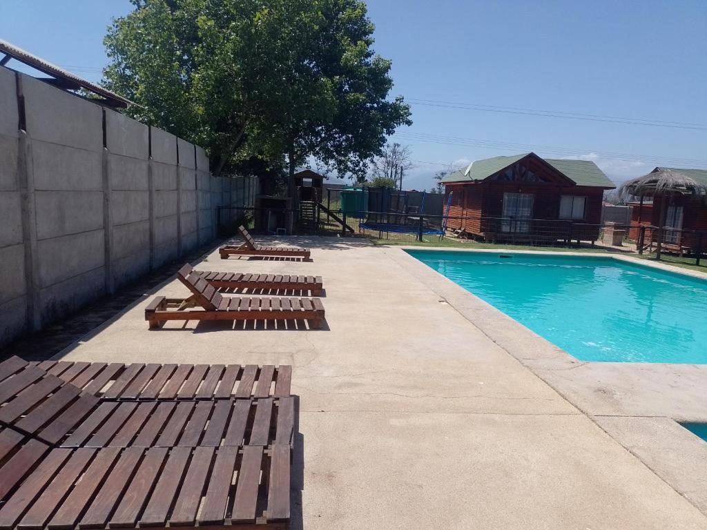 a swimming pool with wooden lounge chairs next to it at Cabañas Marlen in Limache