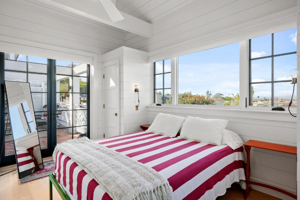een witte slaapkamer met een gestreept bed en grote ramen bij Coastal La Jolla Luxury - AC & Large Ocean View Patio! in San Diego