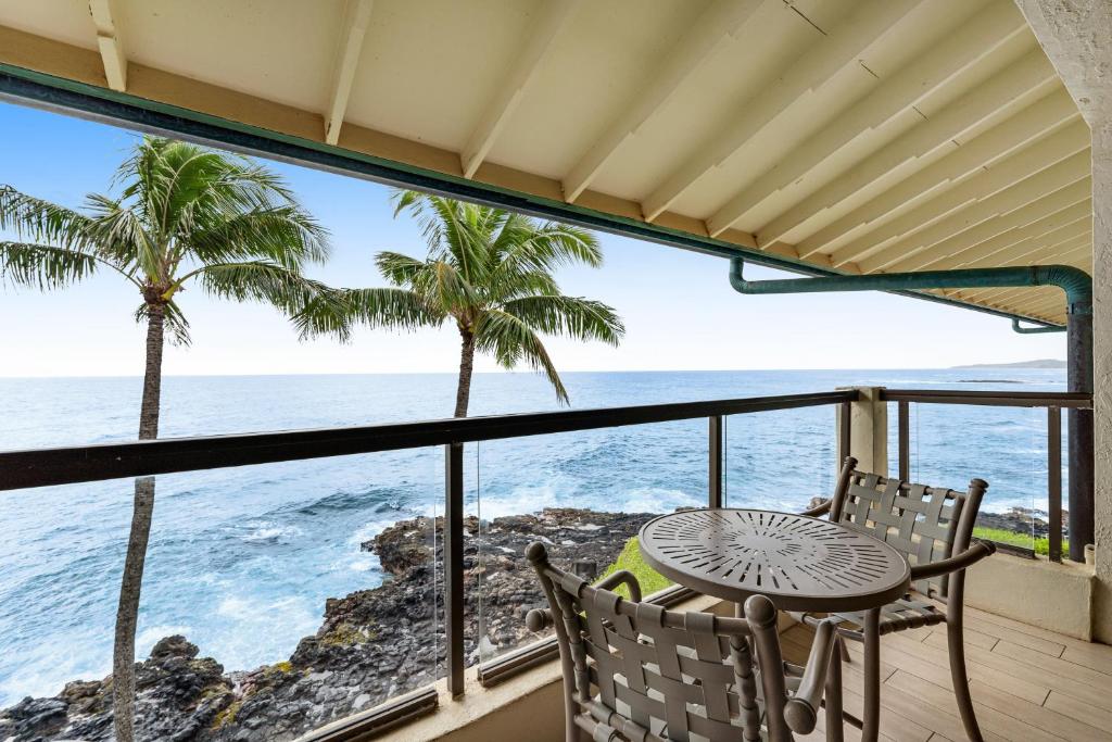 a balcony with a table and chairs and the ocean at Poipu Shores 403A in Koloa