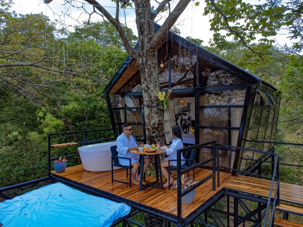 - un couple assis sur le pont d'une cabane dans les arbres dans l'établissement Tree House Glamping, à Yopal