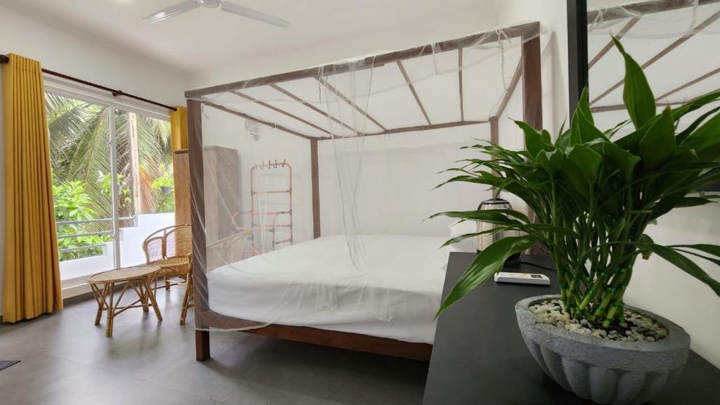a bedroom with a canopy bed with a potted plant at E Seven House in Dickwella