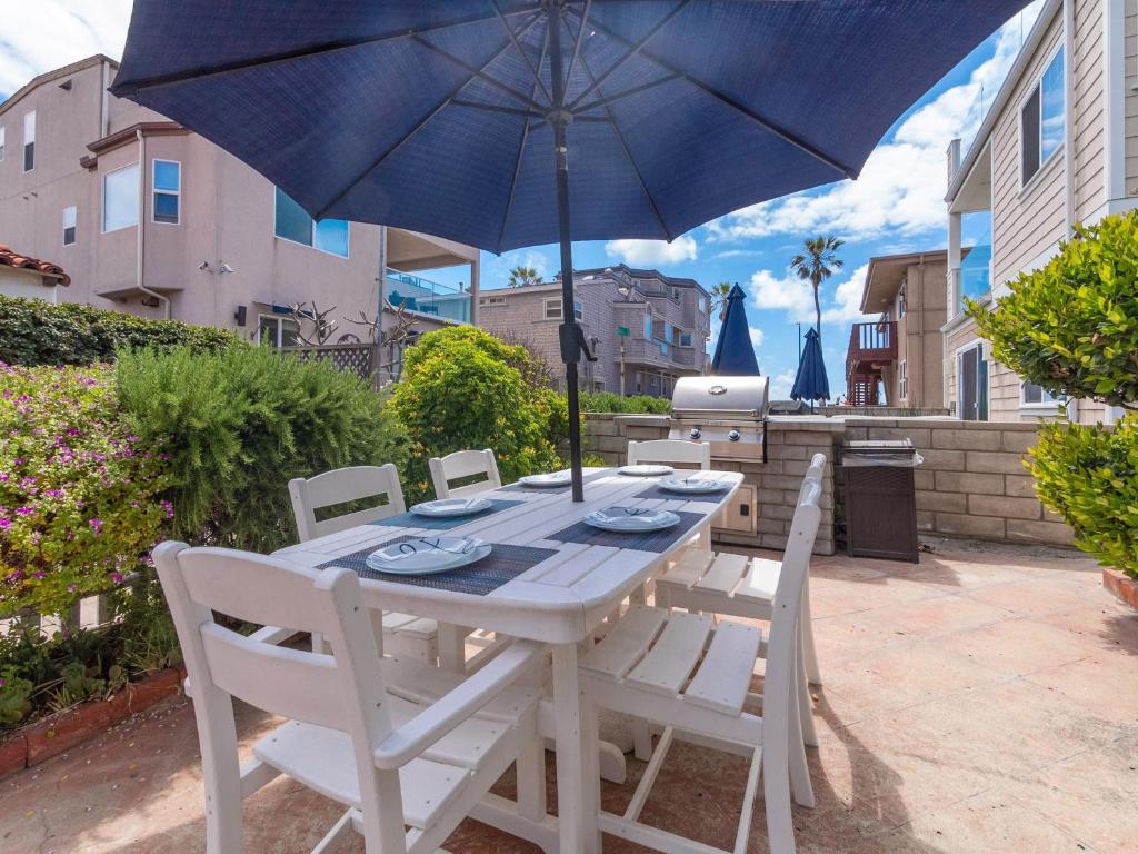 een tafel en stoelen met een parasol op een patio bij Stunning beach home - steps2sand, AC, Large Patio and Fast Wifi! in San Diego