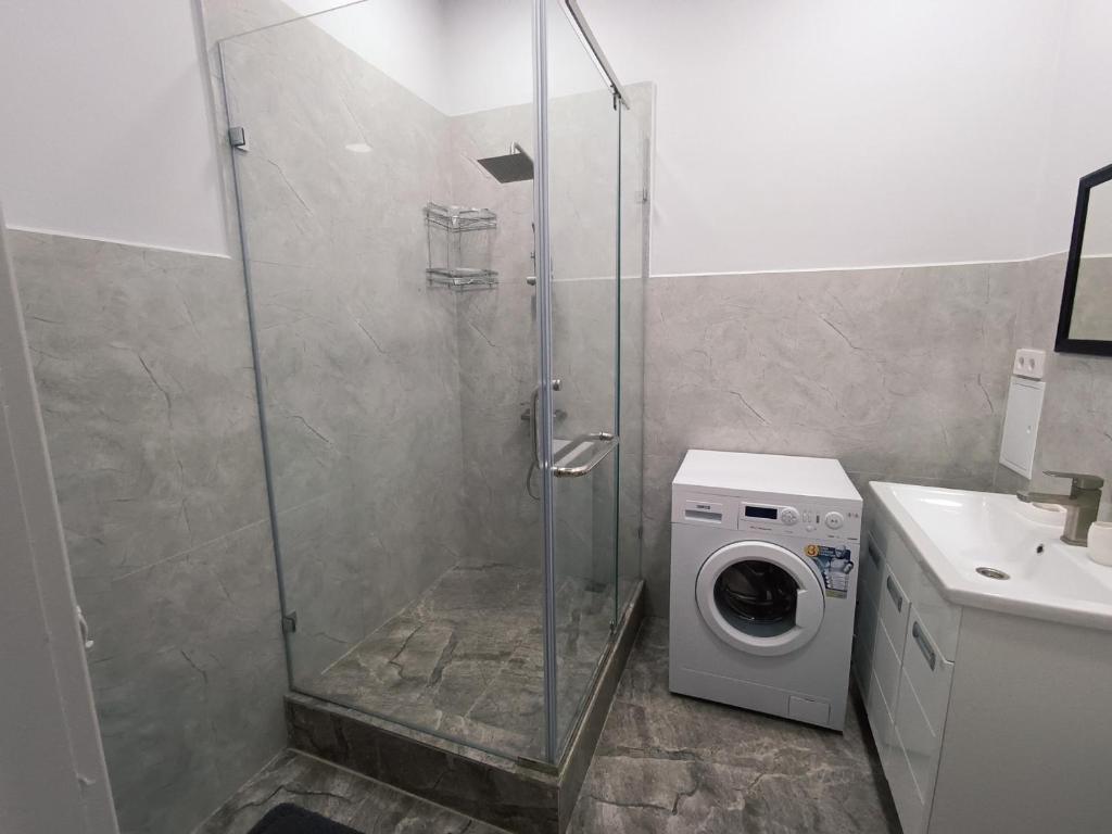 a shower stall with a washing machine in a bathroom at Апартаменты в ЖК Алау in Taldykolʼ