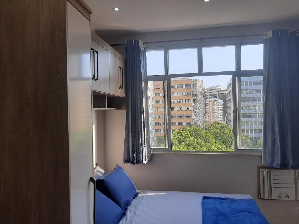 a bedroom with a bed and a large window at Loft Aconchegante no Centro de Niterói!! in Niterói