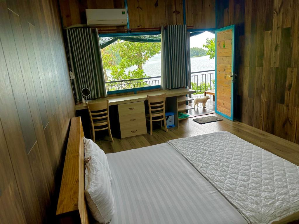 Schlafzimmer mit einem Bett, einem Schreibtisch und einem Fenster in der Unterkunft Bến Hồ Homestay in Xã Gia Tân