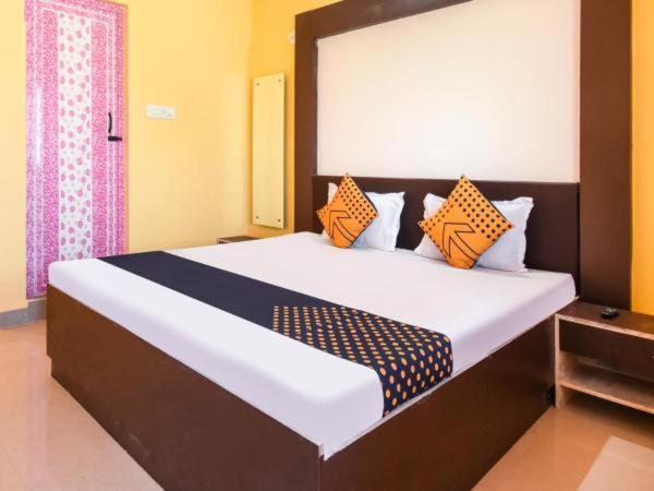 a bedroom with a large bed with orange and blue pillows at HOTEL KK BHAWBAN 1IN PURI in Puri