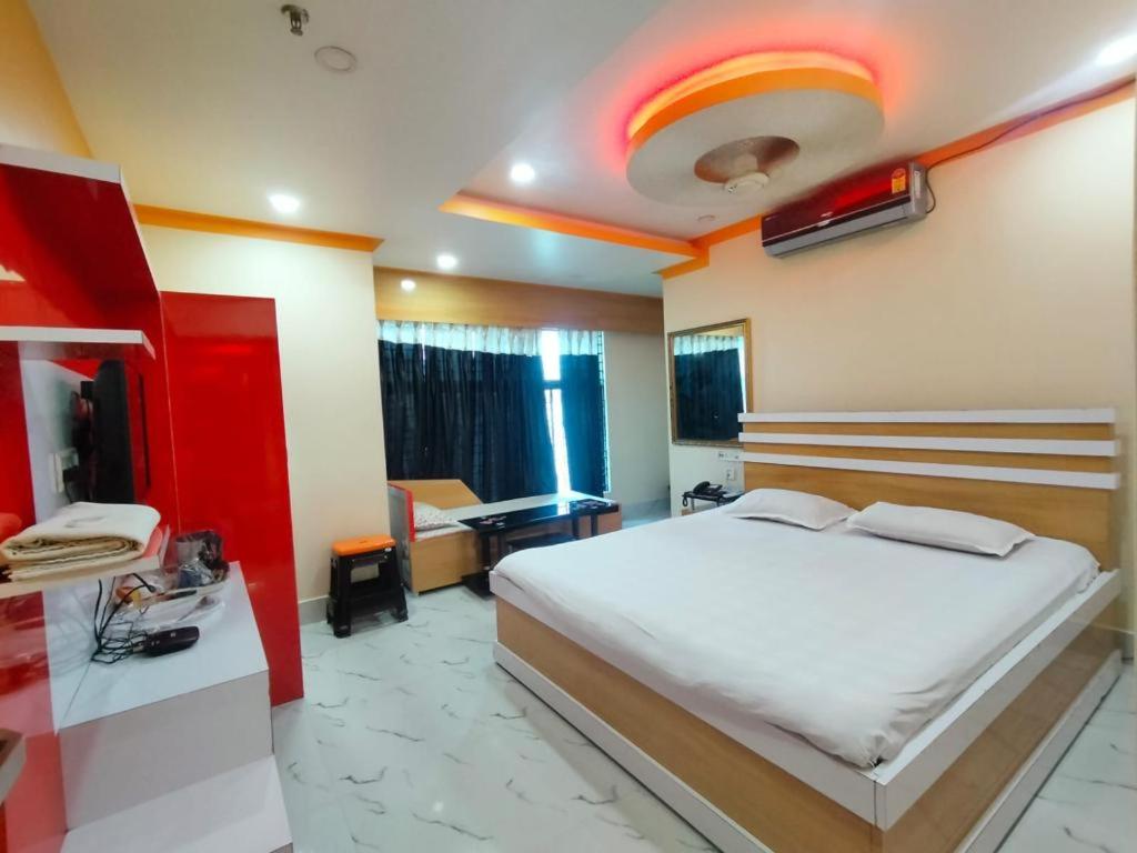 um quarto com uma grande cama branca e uma secretária em Hotel Anurag Palace em Agartala