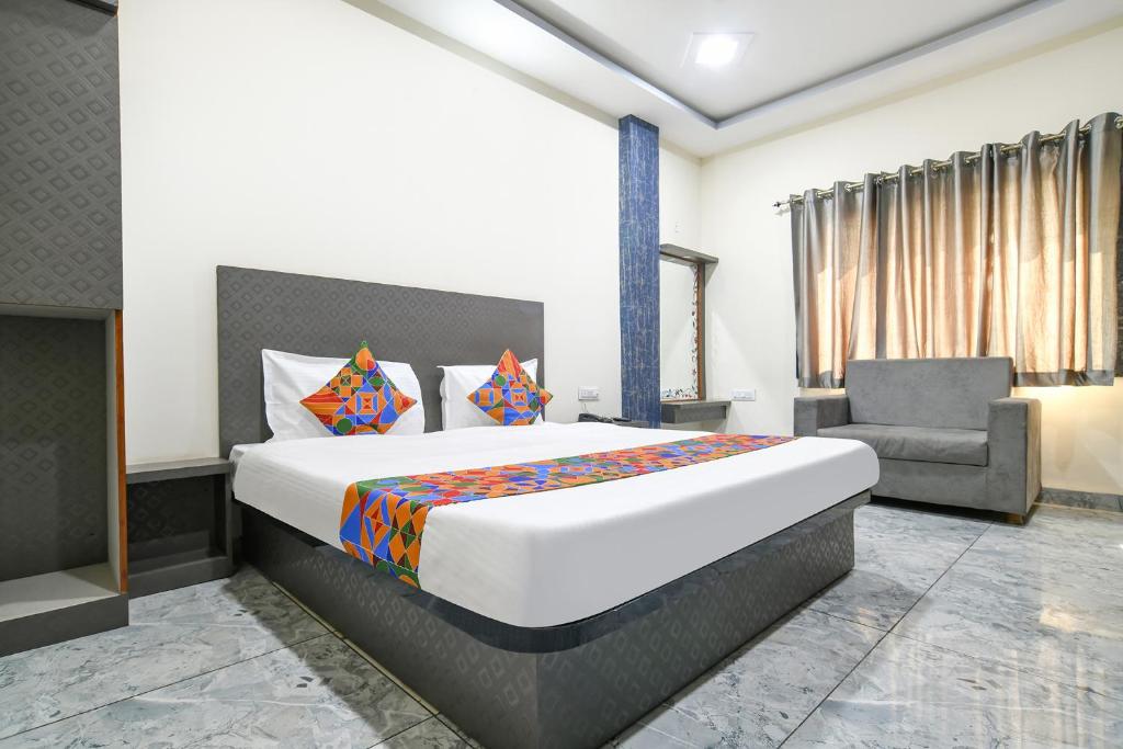 1 dormitorio con 1 cama grande y 1 silla en FabHotel Shree Khatu Shyam Palace, en Indore