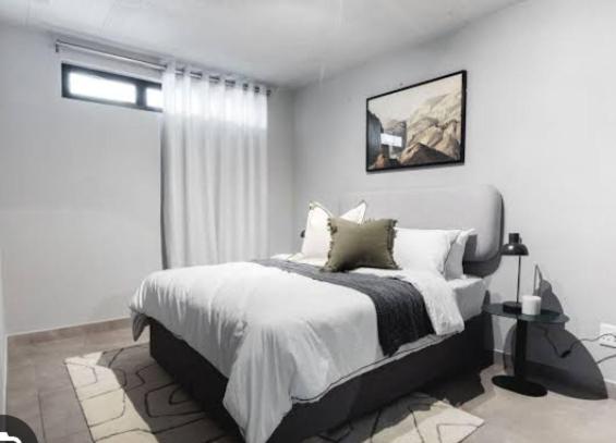 - une chambre blanche avec un grand lit et une fenêtre dans l'établissement Circa unit 91, à Pretoria