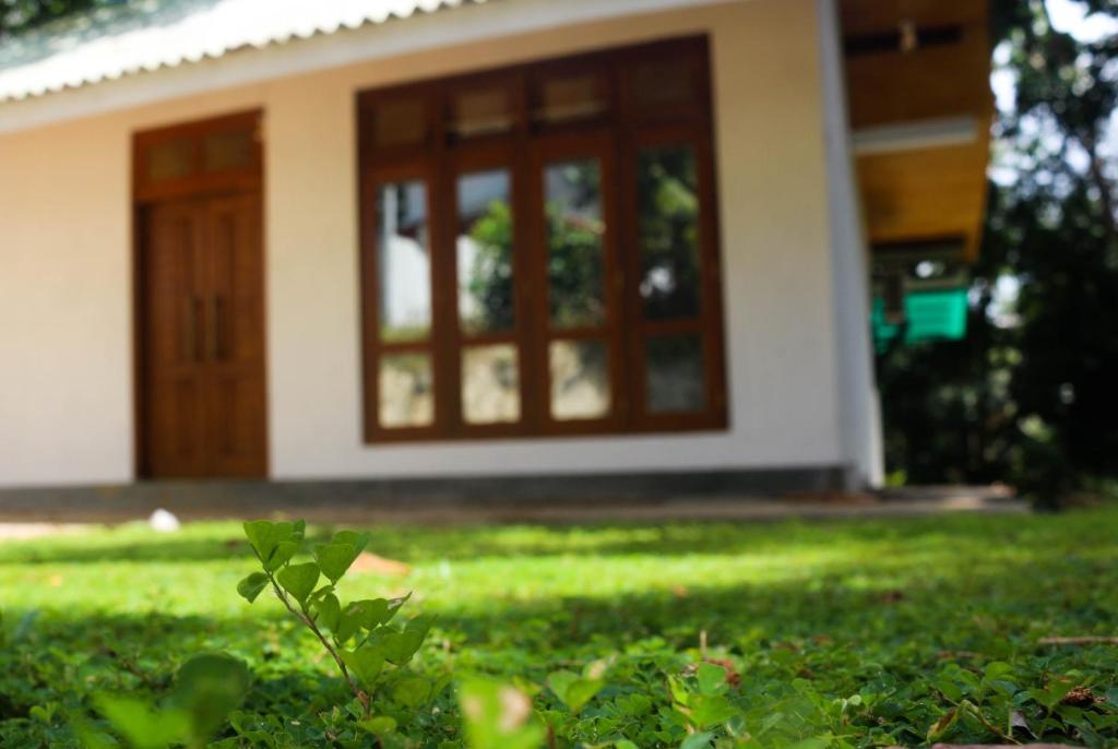 a house with a door and a yard with green grass at Cinnamon eco villa in Hikkaduwa