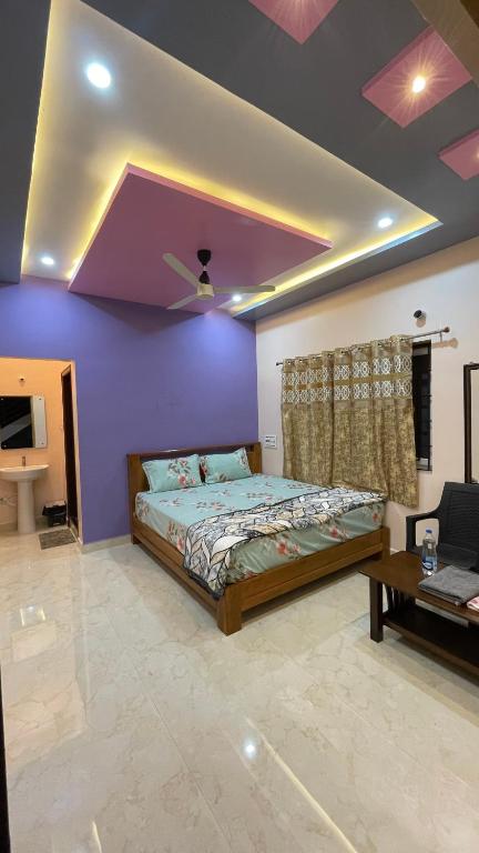 a bedroom with a bed and a purple wall at Mamatha Guest inn in Hampi