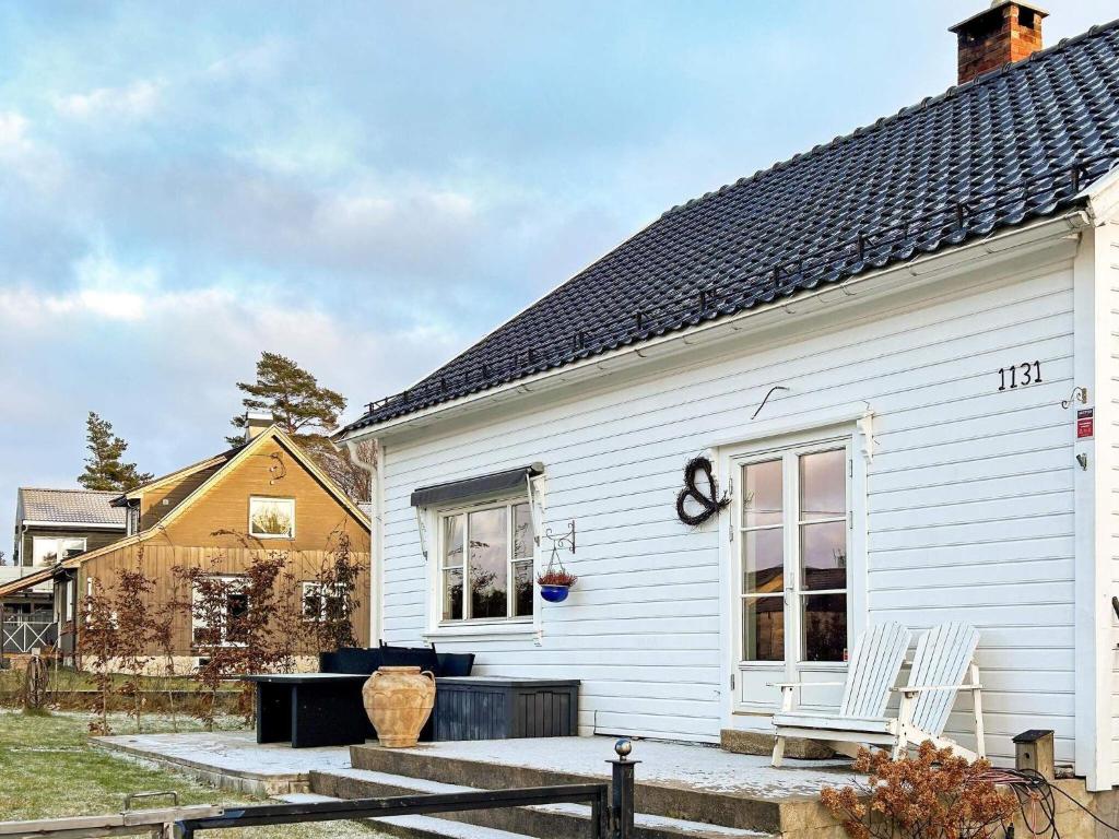 ein weißes Haus mit einem Stuhl auf einer Terrasse in der Unterkunft Holiday home helgeroa in Helgeroa