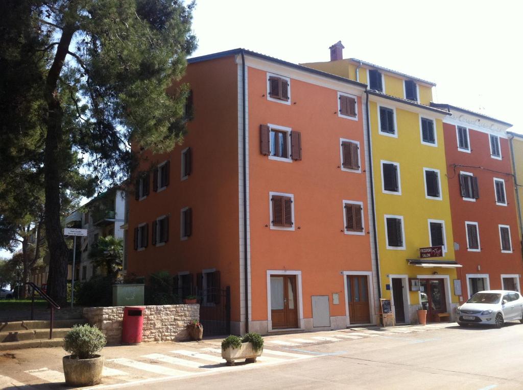 ein gelbes und orangefarbenes Gebäude mit einem Auto, das vorne parkt in der Unterkunft Apartment Sinčić in Novigrad Istria