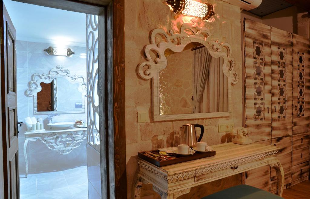 baño con espejo y mesa con lavamanos en ELEVRES STONE HOUSE HOTEL en Urgup