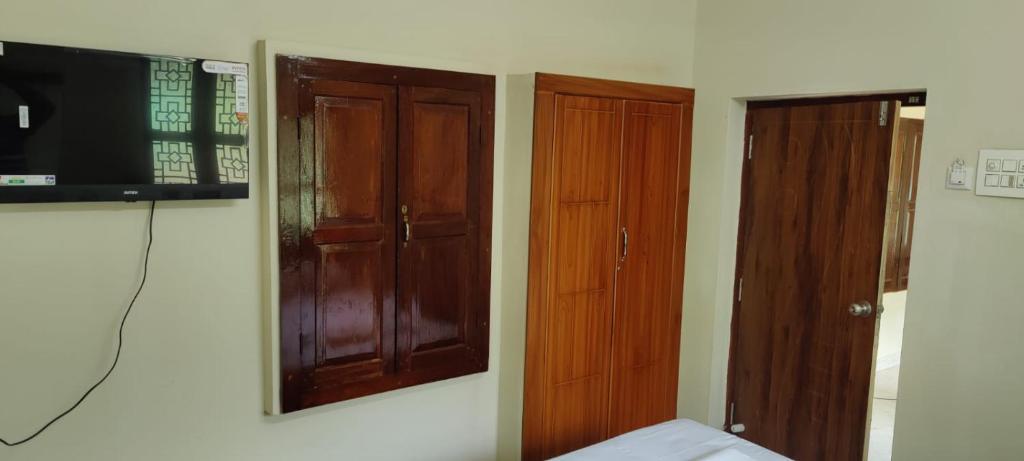 a room with a television and two wooden doors at Beun Residency in Nāgercoil