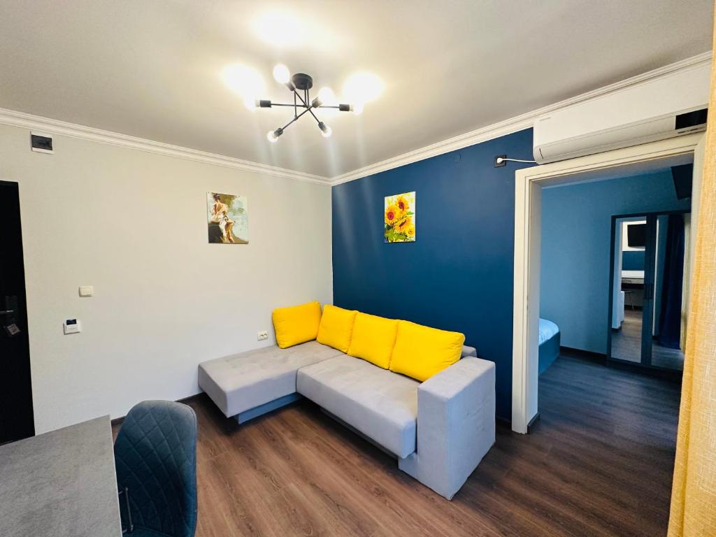 a living room with a couch with yellow cushions at VELI HOUSE VELINGRAD/ ВелиХаус Къща за гости Велинград in Velingrad