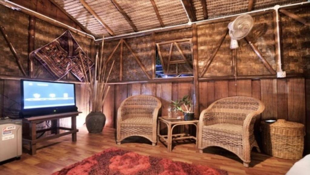 sala de estar con 2 sillas y TV de pantalla plana en Bintan Brzee Beach in Bintan Island - Bungalow 1, en Berakit