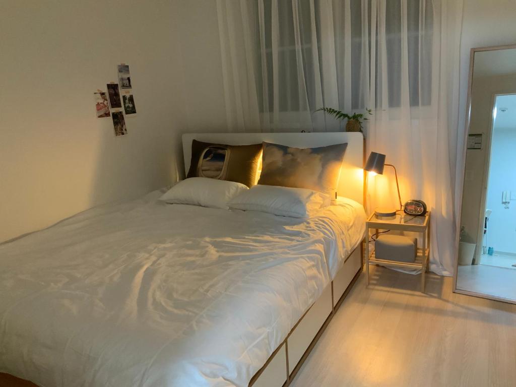 a bedroom with a white bed with a lamp and a window at J-Stay near Hongdae in Seoul