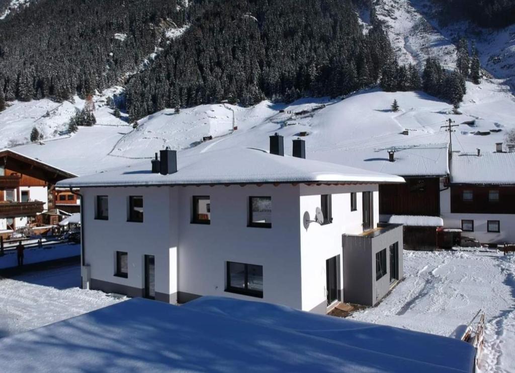 ein weißes Gebäude mit Schnee auf einem Berg in der Unterkunft Apart Madeleine in Sankt Leonhard im Pitztal