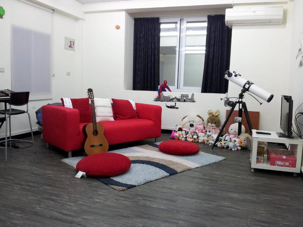 a living room with a red couch and a guitar at Jia Mei Fa Homestay in Taitung City
