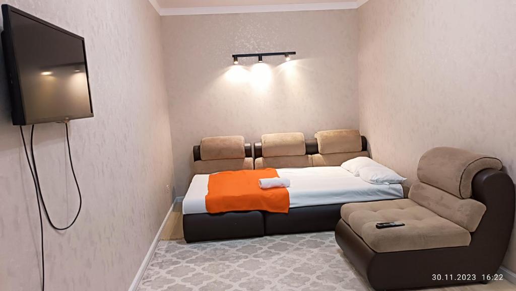 a room with a bed and a chair and a flat screen tv at 1 комн квартира in Taldykolʼ