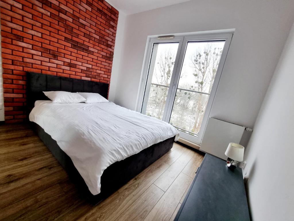 um quarto com uma cama branca e uma parede de tijolos em Przytulny na Winnicy z widokiem na Wisłę em Toruń