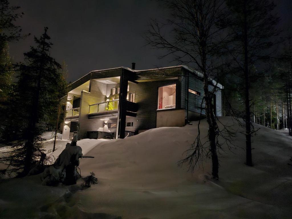 een huis in de sneeuw 's nachts met een persoon voor bij Villa Kanger Ruka1 in Kuusamo