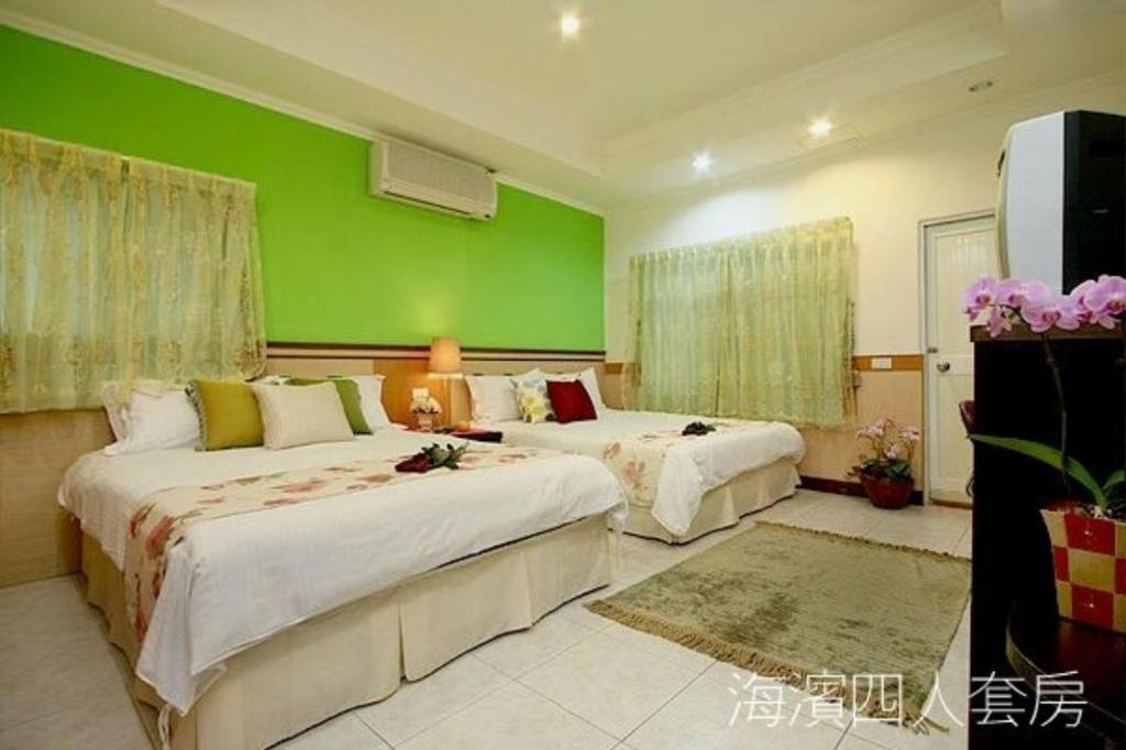 2 camas en una habitación con una pared verde en Hualien Hai Bin Homestay, en Hualien City