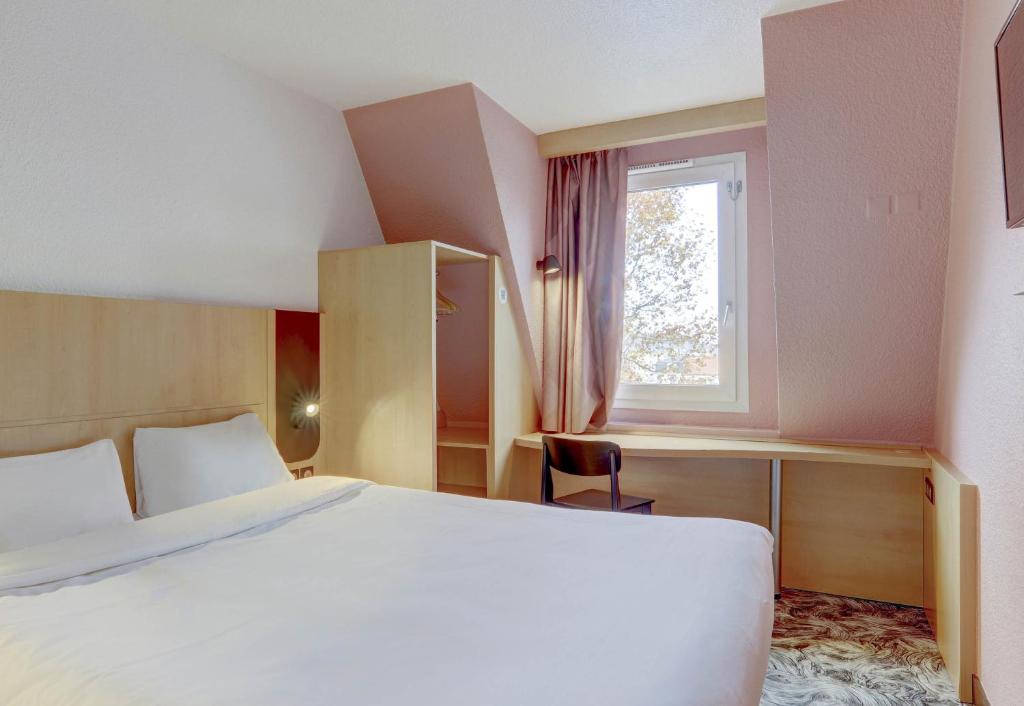 een slaapkamer met een groot bed en een raam bij B&B HOTEL Montluçon Centre in Montluçon