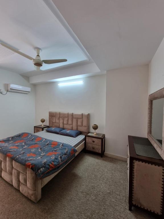 a bedroom with a bed and a ceiling fan at Three Bed Attached Bath Netflix Wifi Smart TV Parking Near Airport in Islamabad