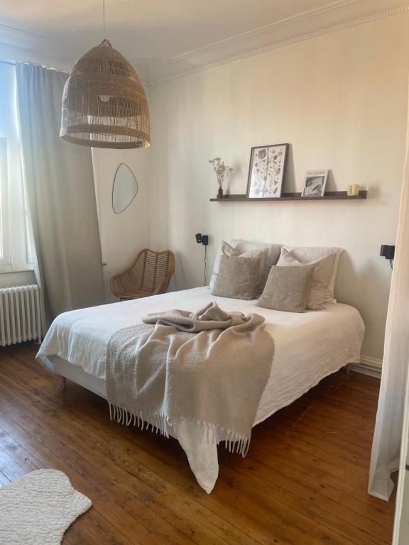 um quarto com uma cama com lençóis brancos e almofadas em Grand appartement charmant à 10 min de Lille em Tourcoing