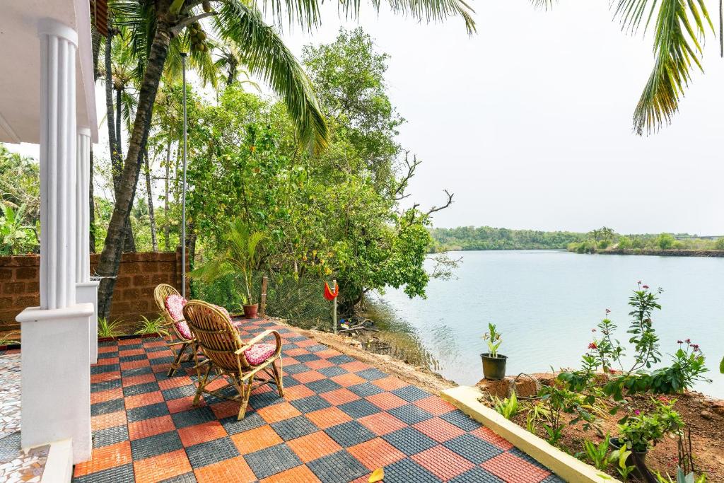 a porch with two chairs and a view of a lake at RiverKiss Villa in Canacona